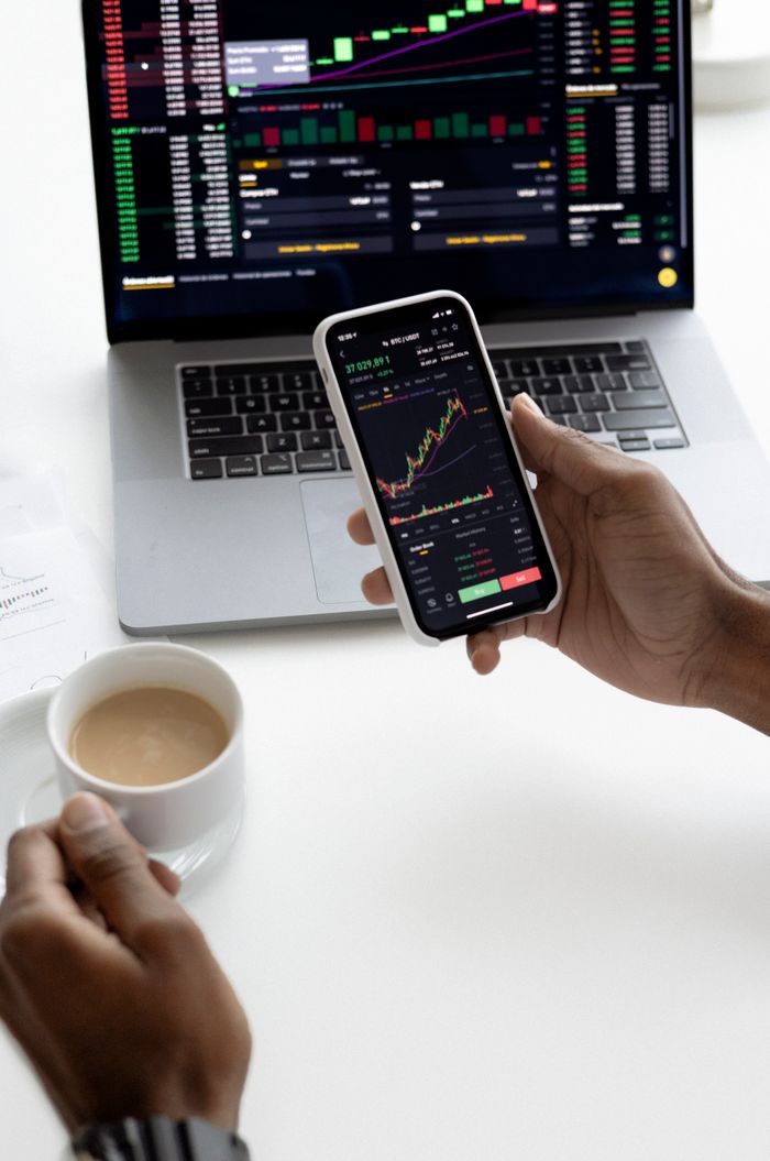 cta-bg Person analyzing stock market trends on smartphone with laptop background